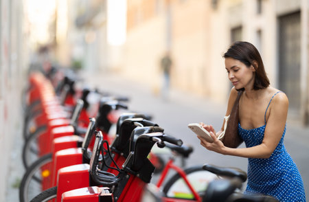 Young woman renting bicycle on city streetの写真素材