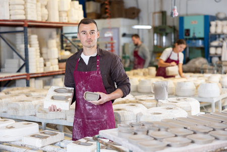 Young man showing poured clay molds