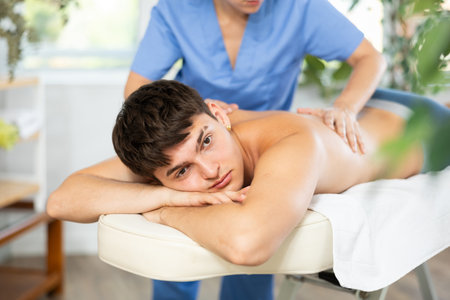 Masseuse doing back massage to young guyの写真素材