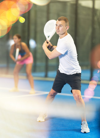 Young woman and man playing doubles tennisの写真素材