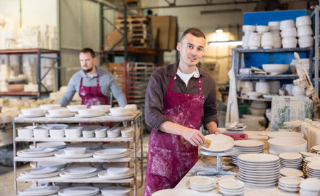 Young man cleaning blanks of ceramic products