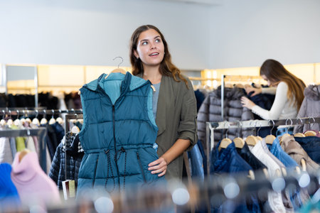 Young woman choosing insulated vest in storeの写真素材