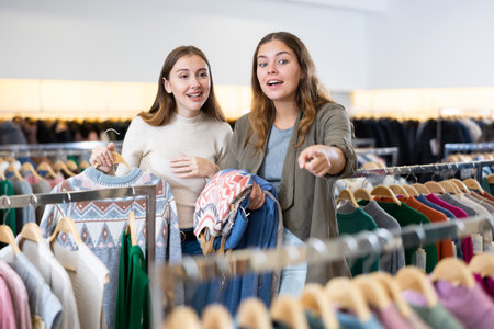 Female friends shopping warm clothes in storeの写真素材
