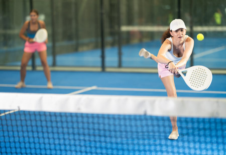 Woman playing padel on indoor court on summer day. Sport and active lifestyle conceptの写真素材