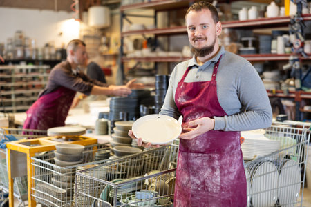 Young man posing with ceramic dishes