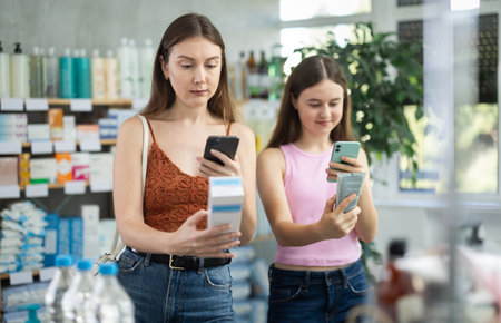 Daughter and mother in summer clothes scans code on skin cream to check expiration dateの写真素材