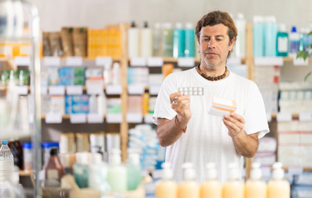 Adult man chooses pills at pharmacyの写真素材