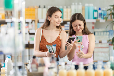Daughter and mother in summer clothes scans code on toothbrush kit to check expiration dateの写真素材