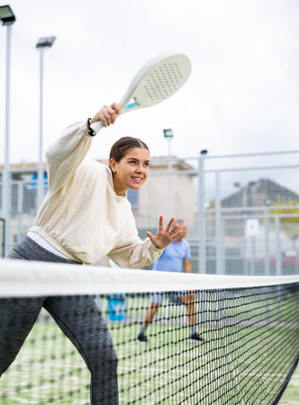 Woman serving ball while playing padel in court during trainingの写真素材