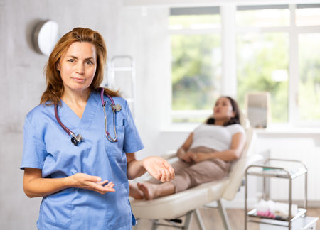 Woman beautician wearing blue overall posing in clinic of esthetic medicineの写真素材