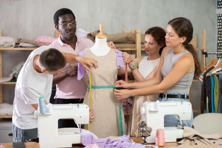 Group of students works with mannequin, checks dimensions of product with centimeter tape