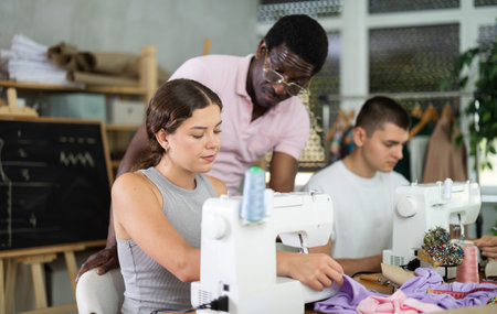 Young woman stitching at machine during sewing class for adultsの写真素材
