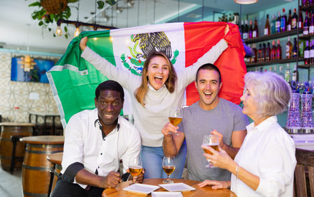 Happy male and female friends or football fans watching soccer on tv and celebrating victory at pub,...