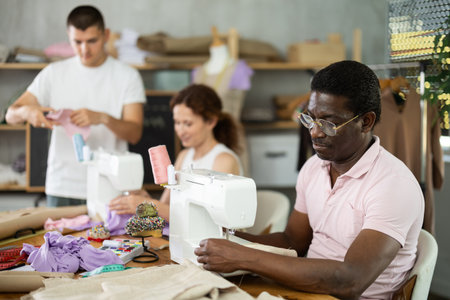 Students work with sewing machines under guidance of teacherの写真素材