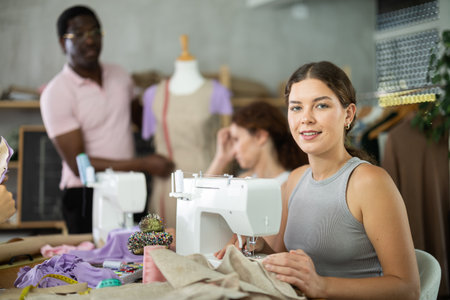 Positive girl working at machine during group sewing course for adultsの写真素材