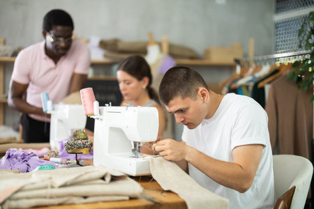 Young man working with sewing-machine during dressmaking coursesの写真素材