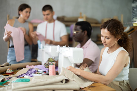 Positive woman working at machine during group sewing course for adults