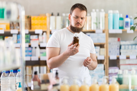 Male shopper carefully reads the name of cough syrup on labelの写真素材
