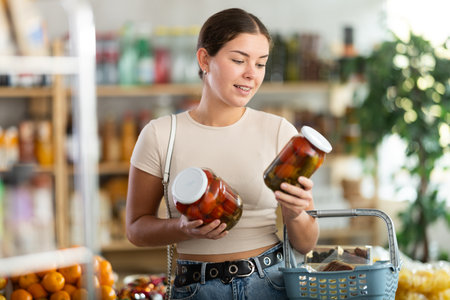 Woman make choice choose consider canned tomatoes in storeの写真素材