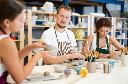 Three students in pottery workshop learn to create homemade plates and other utensils
