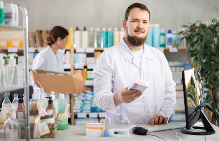 Male pharmacist standing behind counter in pharmacy