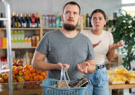 Young woman quarrels with man in grocery storeの写真素材