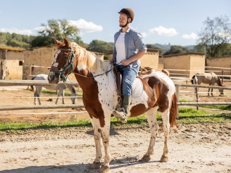 Young man riding horse in paddockの写真素材