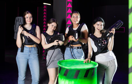 Group portrait of girlfriends with guns in their hands in laser tag roomの写真素材