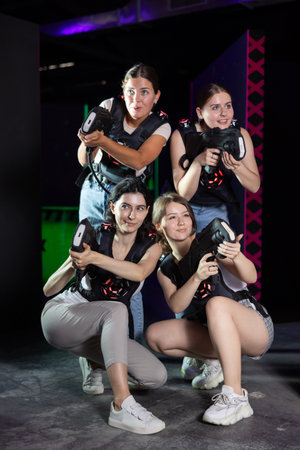 Smiling girlfriends playing laser tag game with colored laserの写真素材