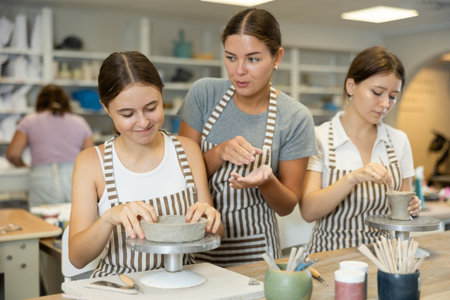 Female teacher explaining to students how to sculpt ceramicsの写真素材