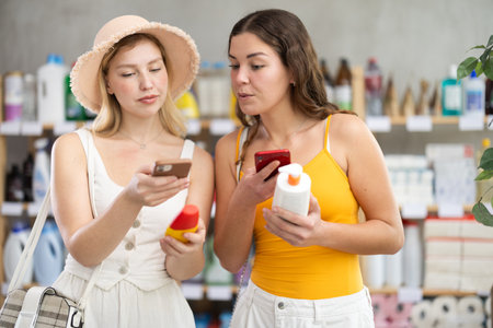 Two friends girls buyer scans qr code on sunblock cream labelの写真素材