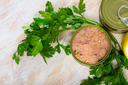 Canned tuna with parsley and lemon on a wooden tableの写真素材