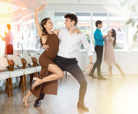 Girl and guy dancing slow ballroom dance during group class in choreography studio