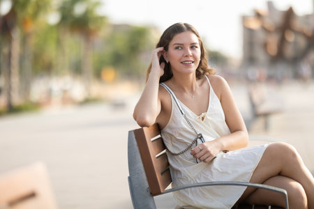 Young woman sits on bench on city streetの写真素材