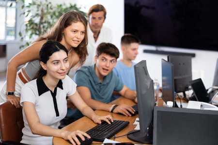 Excited young students engaging in group study session in computer lab