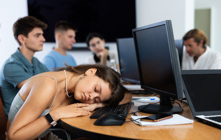 Young female developer tired after workday napping near computerの写真素材