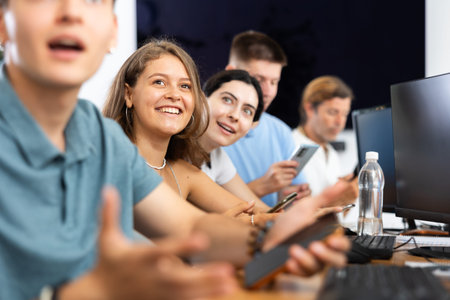 Cheerful young female student using mobile phone in computer workshop