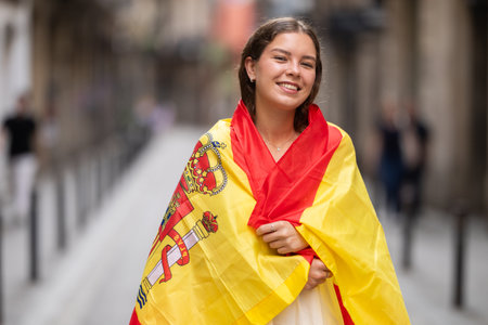 Young woman wrapped in Spanish flag on city streetの写真素材