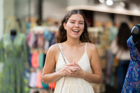 Young girl in white dress is looking for something at street market - looking at goods with interestの写真素材