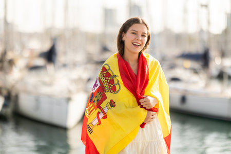 Woman waving national flag of Spain against seaport and yachtsの写真素材