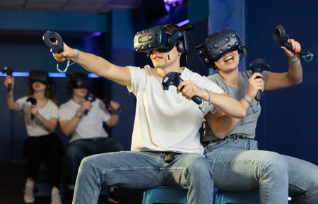 friends in helmets and with joysticks are sitting playing 3d action game. entertainment club
