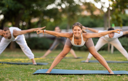 Girl leading outdoor group yoga class in summer parkの写真素材
