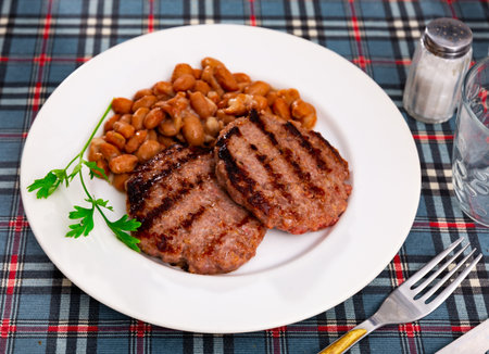 Plate contains light side dish of stewed vegetables - red kidney beans with meat pattyの写真素材