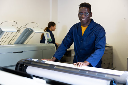 Printing house employee works on printing equipment