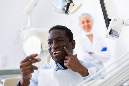 Man looking in mirror to evaluate results of dental restoration procedureの写真素材