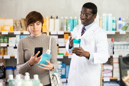 Woman buyer scans mouthwash qr code with woman pharmacistの写真素材