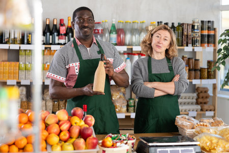 Positive female and male sellers offers choice of various natural food in grocery supermarketの写真素材