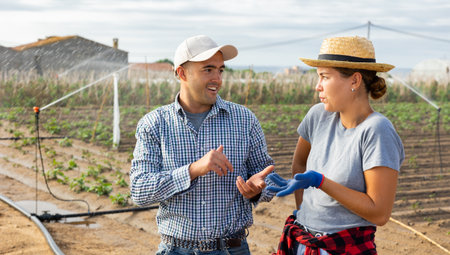 Man and girl farmers talking friendly in field during break in workの写真素材
