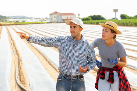Farmer giving instructions to young female worker at farm fieldの写真素材