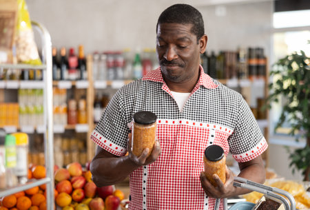 African man make choice choose consider canned pickled lentil in storeの写真素材